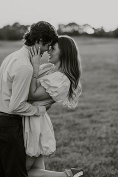 a man and woman kissing in the middle of a field