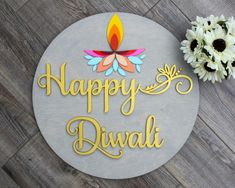 a sign that says happy diwali on it next to some flowers and a potted plant