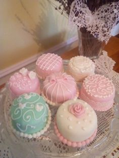 there are many decorated cupcakes on the glass platter with lace doily