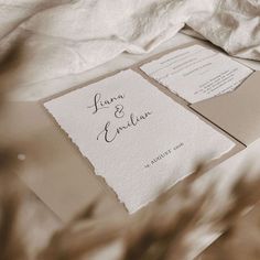 the wedding stationery is laid out on top of the bed sheets and linens