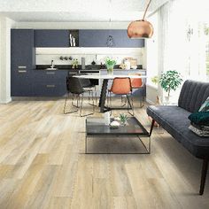 a living room filled with furniture next to a kitchen and dining room table on top of a hard wood floor