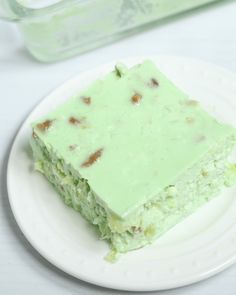 a piece of green cake sitting on top of a white plate next to a plastic container