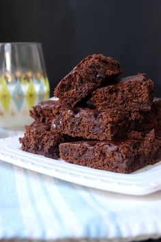 chocolate brownies stacked on top of each other on a plate next to a glass of wine