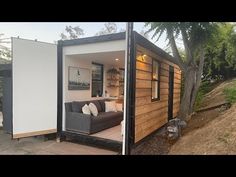 a tiny house built into the side of a hill with its door open and couch inside