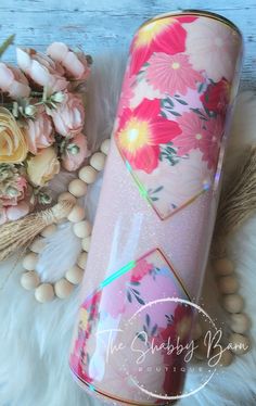 a pink and yellow floral tumbler next to some flowers