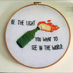 a hand embroidered hoop hanging on the wall with an embroidery pattern that says, be the light you want to see in the world