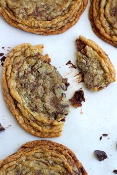 chocolate chip cookies on a baking sheet with one broken in half and the other partially eaten