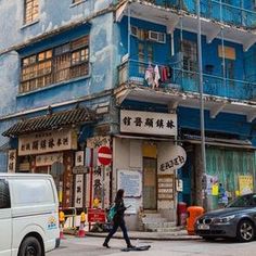 a person crossing the street in front of a building with blue balconies on it