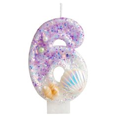 the number six candle is decorated with seashells, pearls and other sea creatures