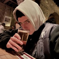 a man sitting at a table with a glass of beer in front of his face