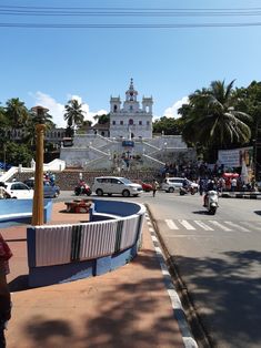 a city street filled with lots of traffic next to tall white buildings and palm trees