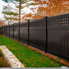 a black fence in front of a house with green grass and trees around the perimeter