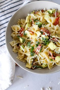 a bowl filled with pasta and vegetables on top of a white table cloth next to a fork