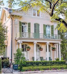 a large white house with green shutters and balconies on the second story