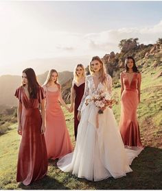 a group of women standing on top of a lush green hillside next to each other