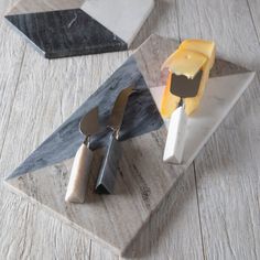 two cheeses on marble stand next to each other with spoons and knives sticking out of them