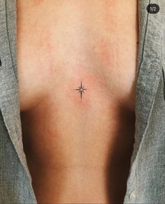 a woman's chest with a small cross tattoo on her left side ribcage