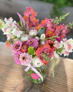 a vase filled with pink and white flowers on top of a wooden table