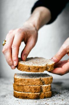 two hands reaching for slices of bread on top of each other