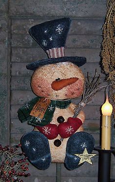 a snowman ornament sitting on top of a table next to a lit candle