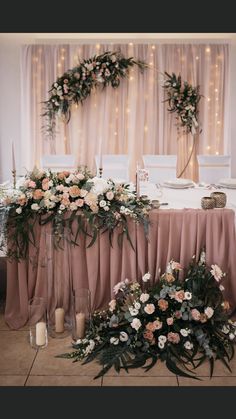 an arrangement of flowers and greenery on a table at a wedding reception with candles