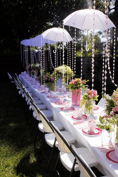 a long table set up with flowers and umbrellas for an outdoor wedding or bridal party