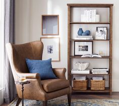 a living room with a chair, bookshelf and pictures on the wall