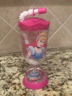 a plastic cup with a pink lid and handle on top of a countertop next to a tile wall