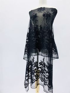 a black lace top on a mannequin with flowers and leaves in the back