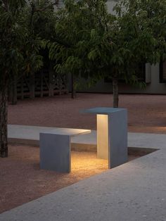 a concrete bench sitting in the middle of a park at night with lights shining on it