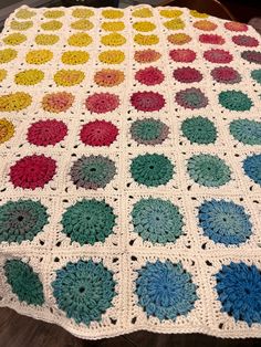 a crocheted blanket with multicolored circles on it sitting on a table