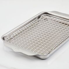 a stainless steel grate on a white surface with the bottom half covered in wire mesh