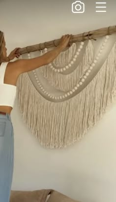 a woman is holding up a curtain made out of fringes and beads on the wall