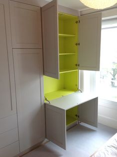 an empty room with white cupboards and yellow shelves on the wall next to a bed