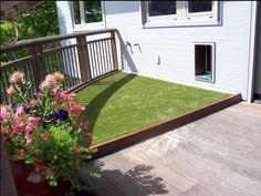 a deck with grass and flowers on it, in front of a blue house that says if beauty is skin deep, how deep is dog growing?