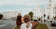 a woman holding a dog in her arms on the street