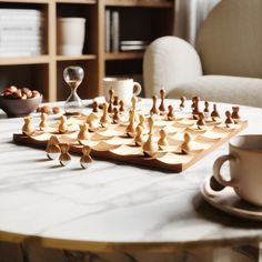 a wooden chess set sitting on top of a table next to a cup and saucer