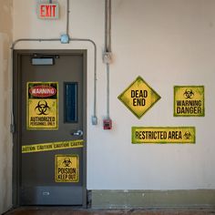 several warning signs are posted on the wall next to an open door with a dead end and restricted area