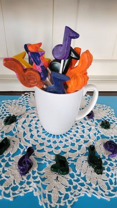 a cup filled with lots of colorful magnets on top of a doily