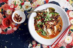 a white bowl filled with soup next to chopsticks on a floral table cloth