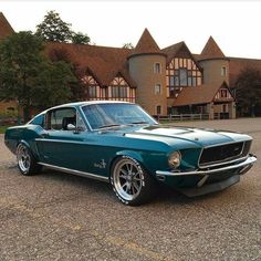 a green mustang parked in front of a large building with two story brown brick buildings