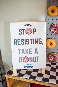 a sign that says stop resisting, take a donut next to some doughnuts