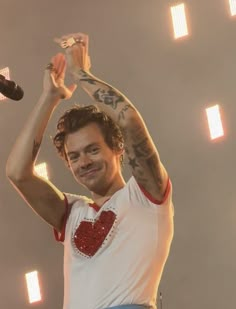 a man holding his hands up in the air while standing on stage at a concert