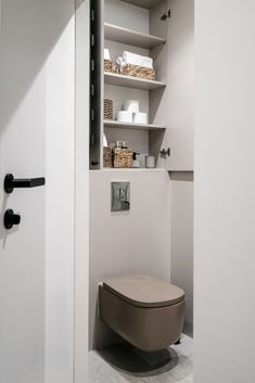 a toilet in a bathroom with shelves above it