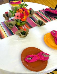 the table is set with colorful plates and napkins