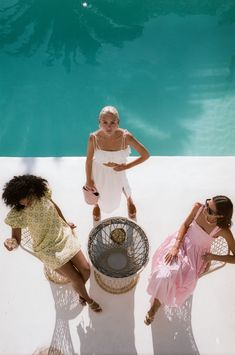 three women sitting on the edge of a swimming pool