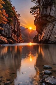 the sun is setting over a mountain lake with rocks and trees in front of it