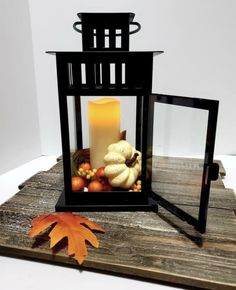 a candle is sitting in a lantern with autumn leaves and pumpkins on the table