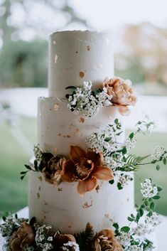 a three tiered cake with flowers and greenery on top