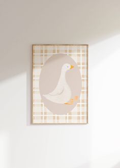 a white duck sitting on top of a wooden floor next to a wall mounted art piece